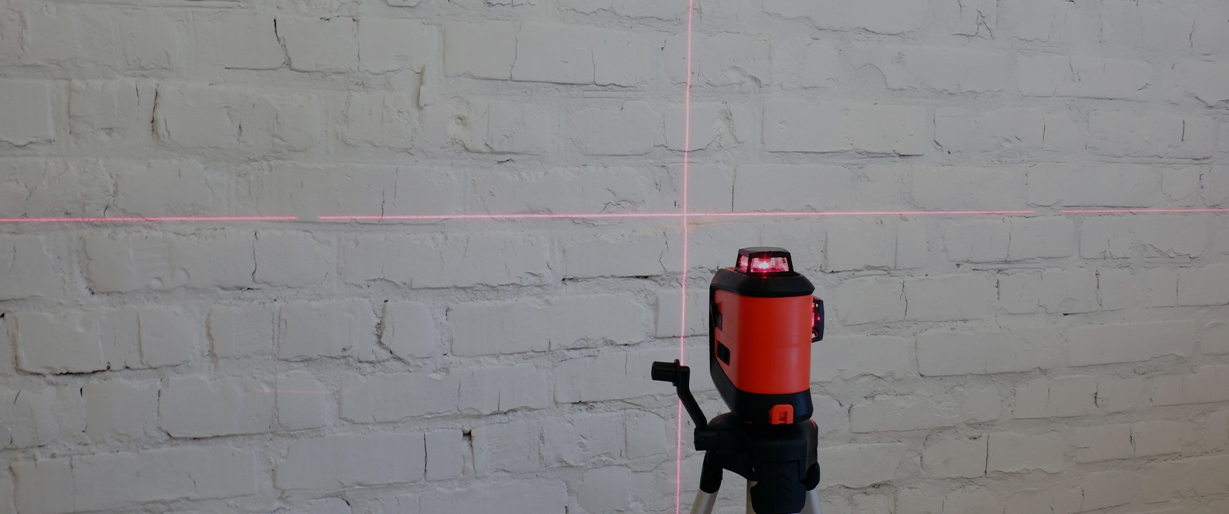Lasermessgerät projiziert Messlinien auf eine Wand beim Aufmaß einer Wohnung